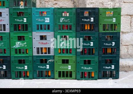TRANI, ITALY - APRIL 20, 2026: Returnable glass bottles of Ferrarelle water in plastic crates in the street in Trani, Italy. Stock Photo
