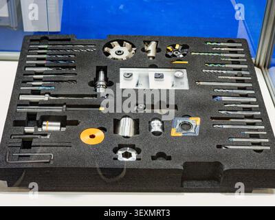 A comprehensive set of metalworking cutting tools, including end mills, drill bits, and indexable milling cutters, neatly organized in a custom black Stock Photo