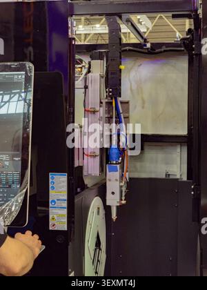 An operator controls a high-tech CNC fiber laser cutting machine designed for precise metal processing in a manufacturing facility. Stock Photo