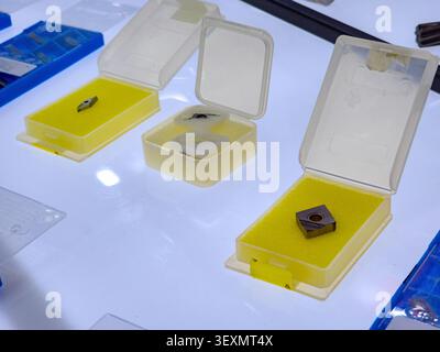 A close-up shot of metal carbide cutting inserts used for CNC milling and turning, organized in protective plastic display boxes with yellow foam lini Stock Photo