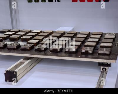 An industrial electro-permanent magnetic chuck holding multiple square steel workpieces on a CNC milling machine table, showcasing advanced workholdin Stock Photo