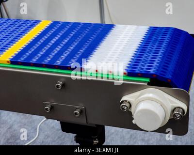 Close-up of a modern multi-colored modular plastic conveyor belt installed on a stainless steel structure, designed for automated manufacturing and fo Stock Photo