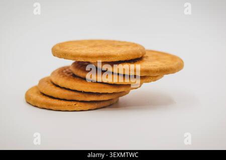 Stack of Round Golden Brown Biscuits on a White Background, Leaning Stack of Round Crispy Biscuits Stock Photo