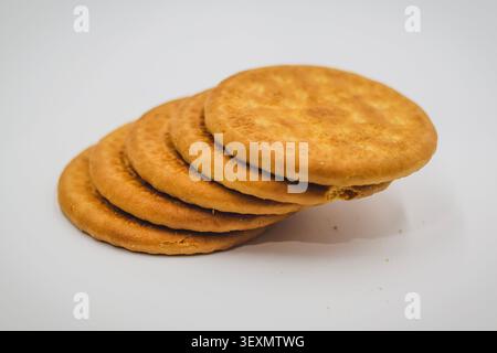 Stack of Round Golden Brown Biscuits on a White Background, Leaning Stack of Round Crispy Biscuits Stock Photo