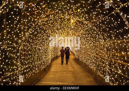 Atmospheric view inside the light tunnel in Isfahan, Iran. The photo captures a couple walking from behind along a path covered by a metal archway str Stock Photo