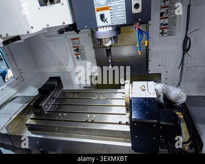Close-up view of a modern CNC milling machine inside an industrial factory, featuring a vertical machining center with a spindle, milling cutter, and Stock Photo