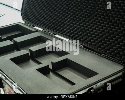 An open heavy-duty hard plastic protective flight case showing customized black foam compartments and egg-crate foam lining on the lid, designed for s Stock Photo
