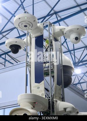 A comprehensive multi-directional CCTV surveillance system featuring various modern dome and PTZ security cameras mounted on a metal truss pillar for Stock Photo