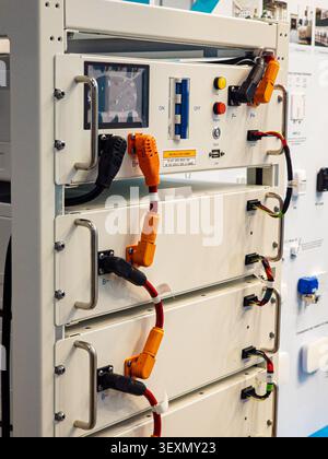 A modern lithium battery energy storage system (ESS) mounted in a server rack, featuring thick orange and black power cables, communication wires, and Stock Photo