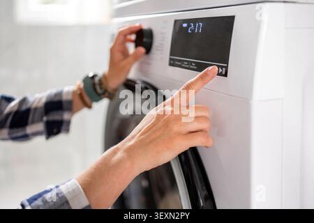 A woman is setting the program on the tumble dryer. Hands close-up Stock Photo