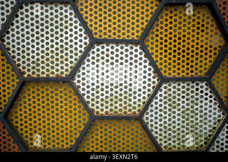 Geometric pattern of honeycomb cells filled with colorful metal. Abstract shapes form a textured mosaic. Stock Photo