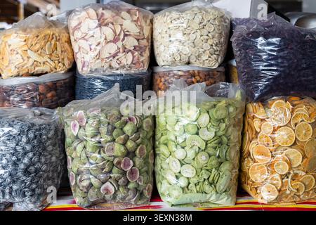 Dried fruits and nuts in plastic bags displayed at Siab bazaar in Samarkand. Colorful variety of figs, kiwi, orange slices, apples, raisins, and almon Stock Photo