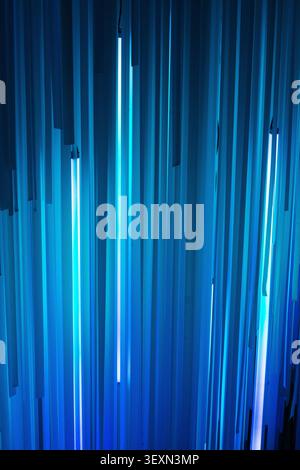 Vertical shot of an abstract geometric pattern with blue vertical panels illuminated by bright neon light tubes. Stock Photo