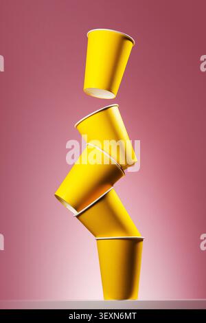 Floating yellow paper cups on pink background Stock Photo