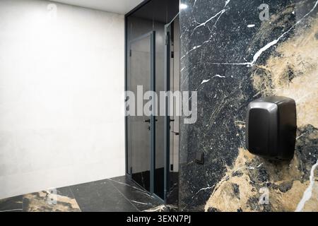 Modern commercial restroom with marble walls, touch free soap dispenser and contemporary interior design. Premium sanitary facilities for office build Stock Photo