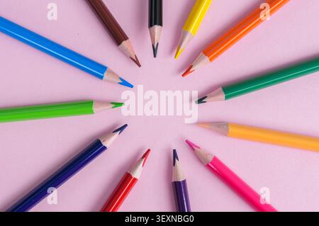 Colored pencils arranged in a circle on a pink background. Stock Photo