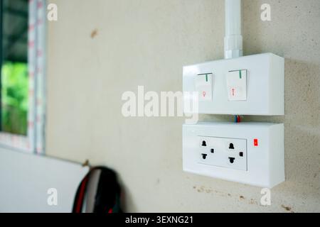 A double light switch dual electrical outlet white plastic mounted on beige wall modern home interior safety feature clean functional convenient pract Stock Photo