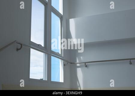 A large window sunlight white wall stainless steel handrail modern interior minimal bright clean architecture daylight reflection glass safety stairwe Stock Photo