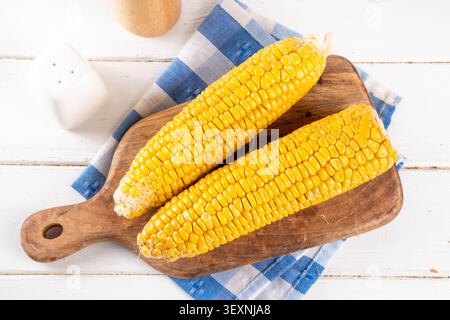 Sweet boiled corn cobs portions on plate, with salt and spices, on white wooden table copy space Stock Photo