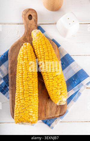 Sweet boiled corn cobs portions on plate, with salt and spices, on white wooden table copy space Stock Photo