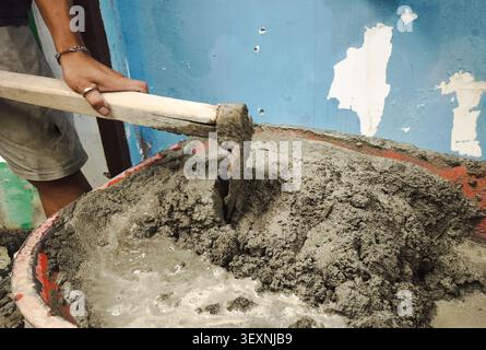 Construction Worker Mixing Wet Cement with Hoe in Mortar Tub for Masonry and Concrete Building Work Close Up Stock Photo