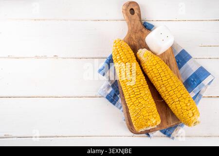 Sweet boiled corn cobs portions on plate, with salt and spices, on white wooden table copy space Stock Photo