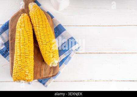 Sweet boiled corn cobs portions on plate, with salt and spices, on white wooden table copy space Stock Photo
