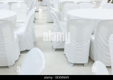 A white chair white table event banquet wedding celebration reception elegant decoration indoor formal cover fabric arrangement round table seat party Stock Photo