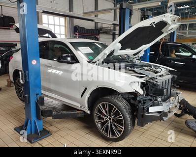 Everyday work of auto mechanics: modern car partially disassembled after an accident on a lift in an auto repair shop Stock Photo