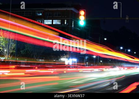 Long exposure shot capturing vivid red and orange vehicle light streaks on a night road Stock Photo