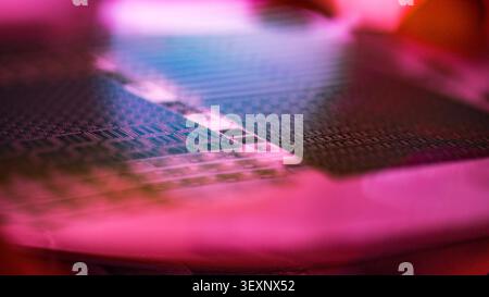 Silicon wafer surface showing intricate patterns of microchips with vibrant neon lighting Stock Photo