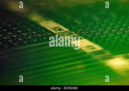 Electronic microchip wafer displaying intricate circuit patterns in green and gold Stock Photo