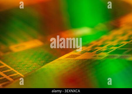 Wafer showing abstract patterns of electronic chips with green and orange reflections Stock Photo