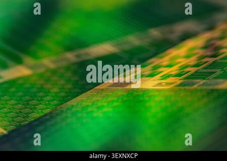 Wafer surface showing circuit patterns for electronic components with green and yellow tones Stock Photo