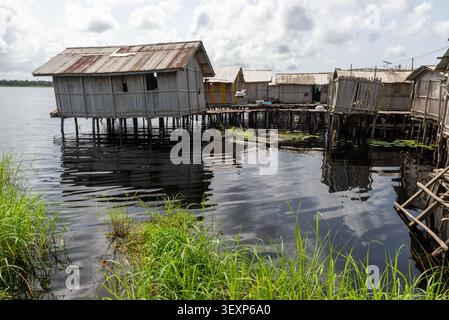 Stilt houses reflected in still lagoon water, Nzulezu village, Ghana Stock Photo