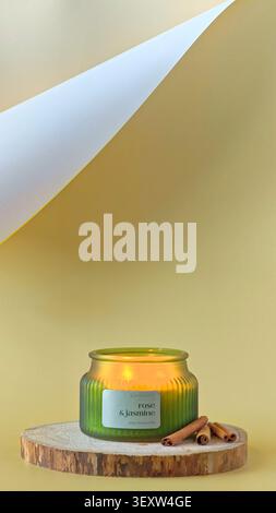 Burning scented candle with a flickering flame inside a green ribbed jar. Cozy, minimalist atmosphere, home decor and wellness aesthetic. Stock Photo