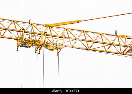 Crane boom and support structure, featuring robust metal framework, bright yellow paint, extending diagonally across frame, minimal sky background, ba Stock Photo