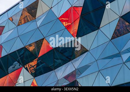 Urban modern architecture, featuring geometric triangular panels, reflective surfaces, dynamic light and shadow play, shades of blue, red and white, i Stock Photo