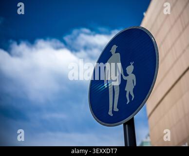 Low angle shot of a blue and white Japanese pedestrian crossing sign under a bright blue cloudy sky. Stock Photo