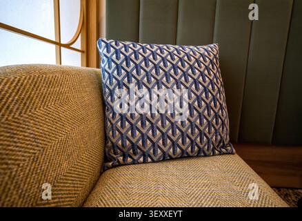A patterned blue and grey throw pillow on a textured chevron sofa in a modern Japanese style interior. Stock Photo