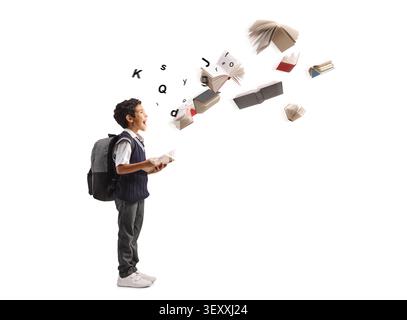 Excited schoolboy with a backpack looking at flying books and letters on a white background Stock Photo