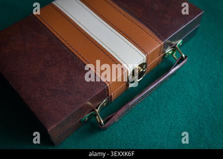 Close-up of a brown leather briefcase placed on a green felt mat, typical of gaming or casino tables. Concept image for business, gambling, money, hig Stock Photo