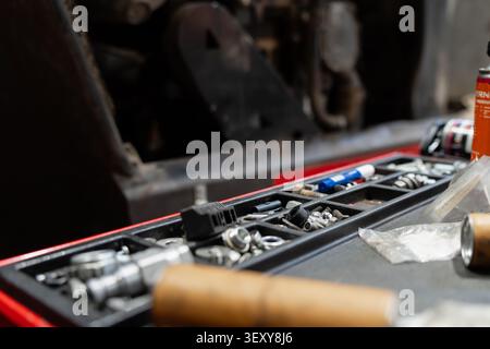 Organizer tray on a workshop cart filled with various metal screws, nuts, washers, and small mechanical components for vehicle maintenance Stock Photo