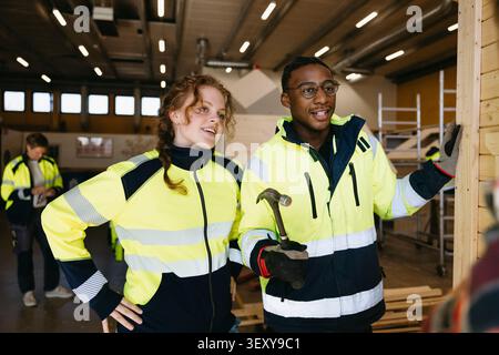 Female and male student wearing reflective jacket studying civil engineering in vocational workshop Stock Photo