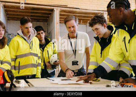 Male vocational instructor teaching students at training session in workshop Stock Photo