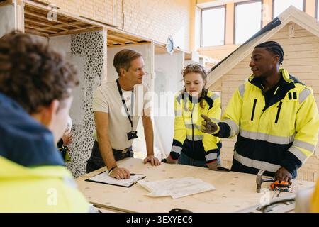Young male student wearing reflective jacket discussing with instructor at civil engineering class in high school Stock Photo