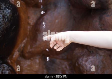 Child hand near falling water drops Stock Photo