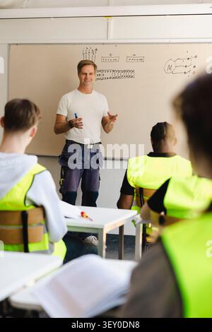 Smiling male professor teaching technical circuitry concepts to vocational students in classroom at school Stock Photo