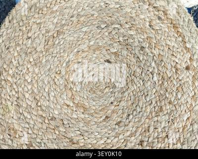 A round mat made from natural fibers showcases a spiral pattern on a flat surface, suitable for various design projects and backgrounds. Stock Photo