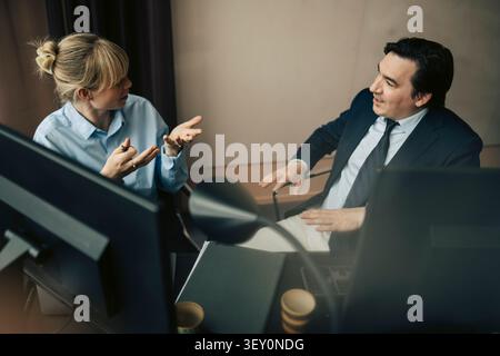 High angle view of male and female business professionals talking with each other at desk in office Stock Photo